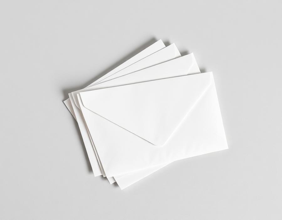 Neat stack of plain white letter envelopes on a light grey surface